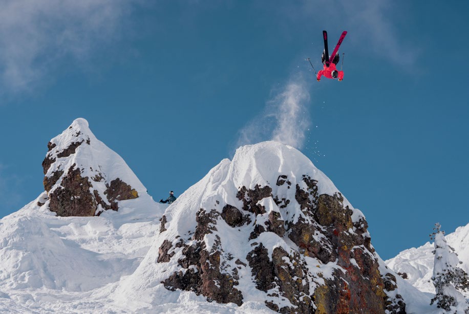 A freeride athlete inverted mid-air above a snow-covered Sierra spine.
